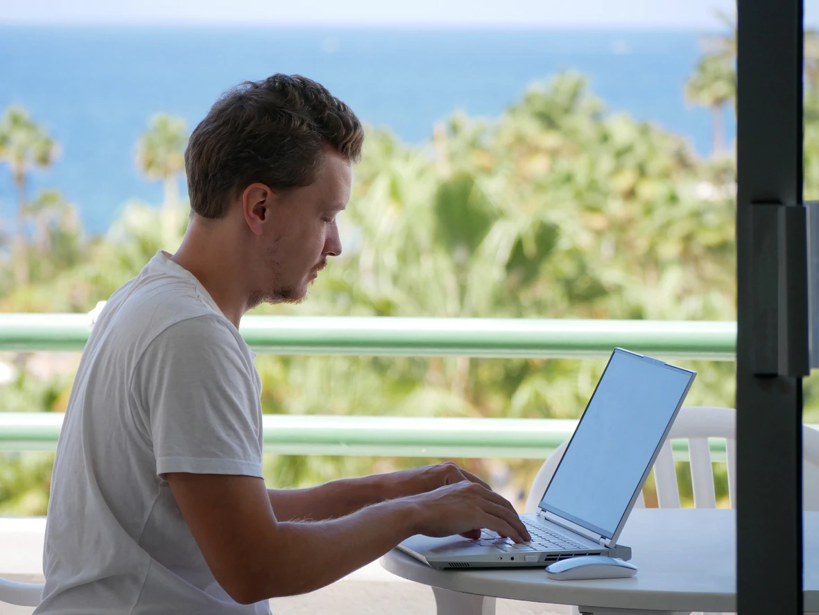 Remote Freelancer Typing on Laptop with Ocean View in Tropical Paradise
